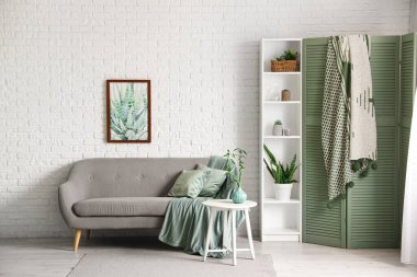 Konforlu kanepesi, raf ünitesi ve katlanır ekranı olan modern oturma odası.