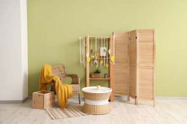 Konforlu koltuk, kahve masası ve modern oturma odasındaki katlanır ekran.