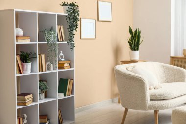 Kitaplık ve ev çiçekleri şık oturma odasındaki beyaz kanepenin yanında.