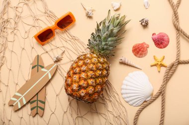 Güneş gözlükleri, ananas, bej arka planda sörf tahtaları ve deniz kabukları. Yaz konsepti