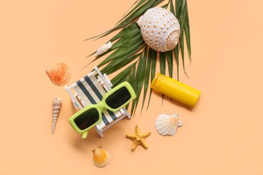 Güneş gözlüğü, iskemle, palmiye yaprakları ve bej arka planda deniz kabukları. Yaz konsepti