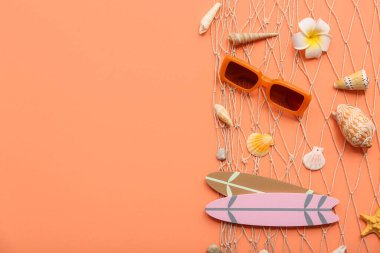 Güzel deniz kabukları, güneş gözlükleri ve turuncu arka planda sörf tahtaları. Yaz konsepti