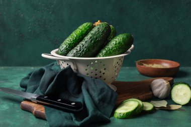 Yeşil arka planda taze salatalıklı Colander.