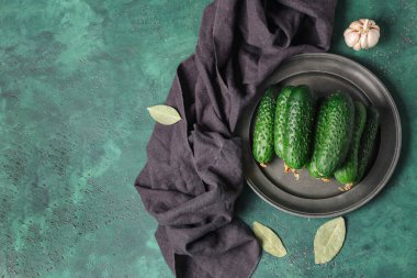 Taze salatalık, defne yaprağı ve yeşil arka planda sarımsak.