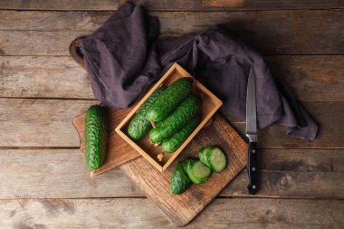 Tahta arka planda yeşil salatalıklı kutu ve tahtalar.