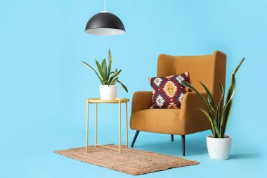 Mavi arka planda bitkileri olan yastıklı rahat bir koltuk.