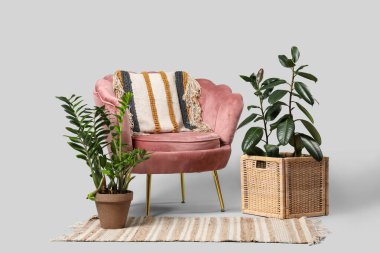 Yastıklı rahat koltuk ve gri arka planda ev bitkileri