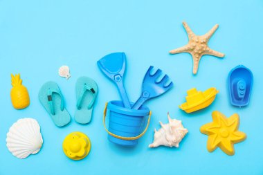 Çocuklar için plaj aksesuarları ve mavi arka planda çocukların parmak arası terlikleri. Üst görünüm