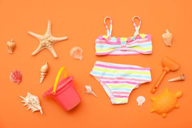 Çocuk mayosu ve turuncu arka plandaki çocuklar için plaj aksesuarları. Üst görünüm