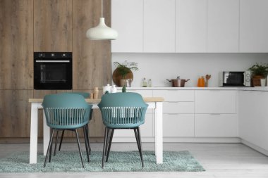 Mutfağın içinde yemek masası ve beyaz tezgahlar var.