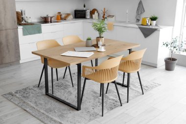 Mutfağın içinde yemek masası ve beyaz tezgahlar var.