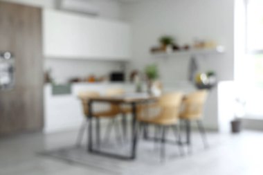 Açık mutfak manzarası bulanık. Yemek masası ve beyaz tezgahlar.