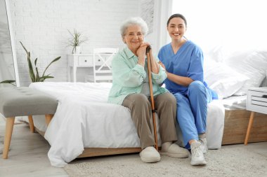 Fizyoterapist ve yatak odasında oturan yaşlı kadın.