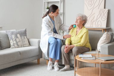 Fizyoterapist yaşlı kadına evde top ile masaj yapıyor.