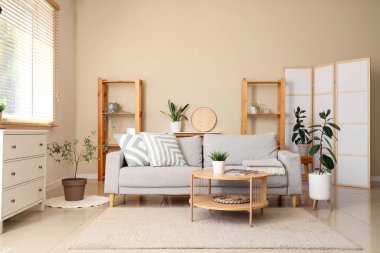 Gri kanepe, sehpa ve bitkilerle oturma odasının içinde.