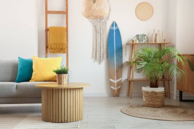 Gri kanepeli, sehpalı, yastıklı ve sörf tahtalı bir oturma odası.