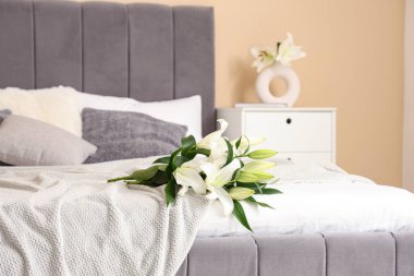 Şık bir yatak odasında, rahat bir yatakta, bir buket nilüfer çiçeği.