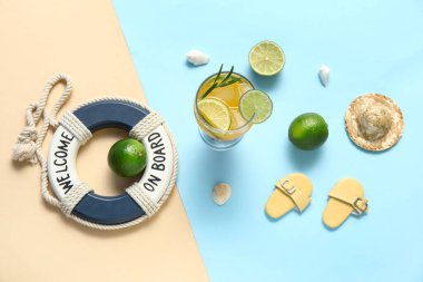 Limonlu bir bardak lezzetli kokteyl, parmak arası terlik, can simidi, kabuk ve renkli arka planda hasır şapka.