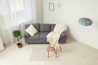 Oturma odasının içinde kitaplarla birlikte ekoseli ve yastıklı rahat bir kanepe.