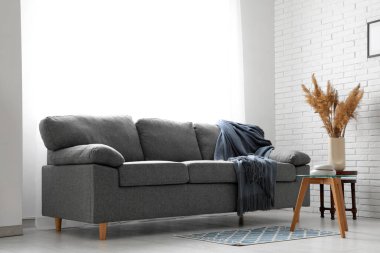 Oturma odasının iç tarafında büyük siyah bir kanepe ve kahve masası.