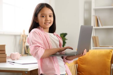 Bilgisayarlı küçük Asyalı kız evde internetten çalışıyor.