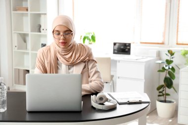 Masada dizüstü bilgisayarla çalışan güzel bir Müslüman iş kadını.