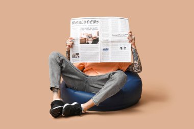 Bej arka planda gazetesi olan puf minderli adam.