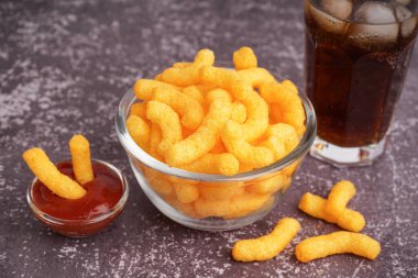 Lezzetli mısır çubukları, bir bardak kola ve arkaplanda ketçap, yakın plan.