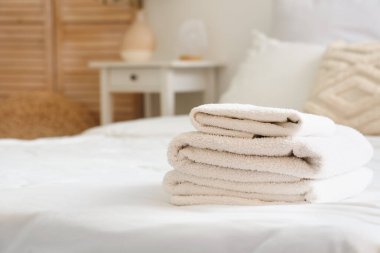 Yatak odasında temiz yumuşak havlular yığını, yakın plan.