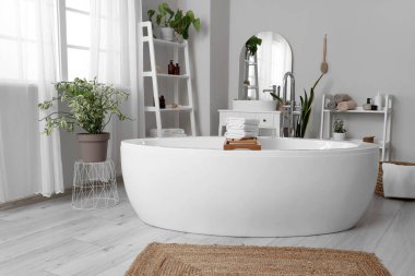 Banyonun içindeki ahşap küvet tepsisinin üzerinde temiz, yumuşak havlular yığını.