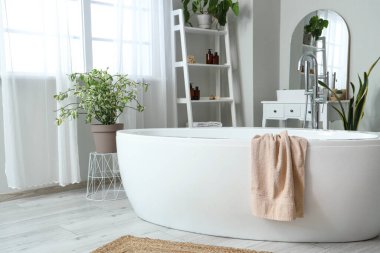 Banyonun içindeki küvette asılı pembe yumuşak havlu.