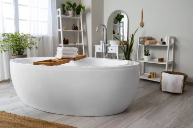 Banyonun içindeki ahşap küvet tepsisinin üzerinde temiz, yumuşak havlular yığını.