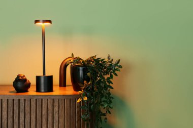 Yeşil duvarın yanında parlayan lamba olan ahşap çekmeceler.