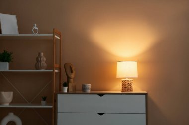 Oturma odasının iç tarafındaki çekmecelerin üzerinde parlayan güzel bir lamba.