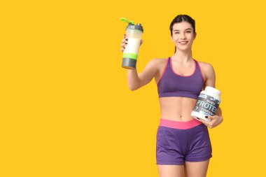 Sarı arka planda protein tozu ve tozu olan güzel, sportif bir kadın.