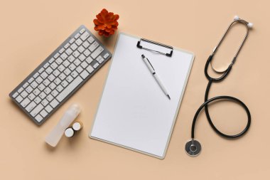 Bej arka planda modern bilgisayar klavyesi, kalem, pano ve steteskop