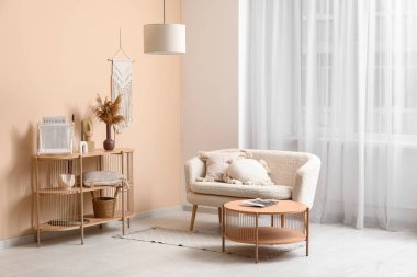 Yastıklı rahat bir kanepe ve oturma odasının iç tarafındaki pencereye yakın dekorlu ahşap raf ünitesi.