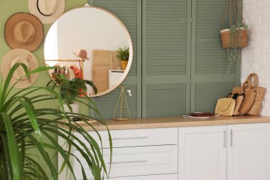 Çiçekler, çekmeceler ve yeşil duvarın yanındaki katlanan ekran.