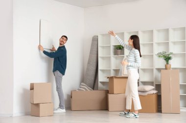 Genç bir çift taşınma gününde duvarlara resim asıyor.