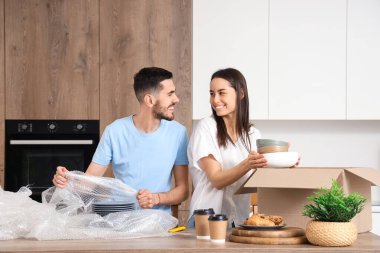 Genç çift taşınma gününde mutfakta bulaşık paketliyor.