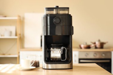 Mutfaktaki masada kahve fincanı ve bir kavanoz fasulye ile modern kahve makinesi.