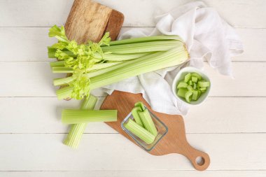 Beyaz ahşap arka planda taze yeşil kereviz tabakları ve yiyecekler.