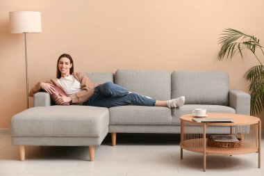 Şık bir oturma odasında kanepede uzanmış genç bir kadın.