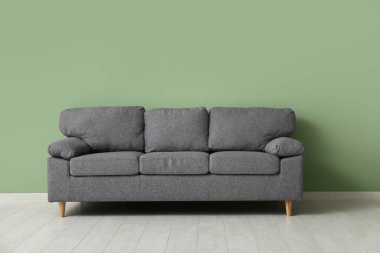 Yeşil duvarın yanındaki rahat kanepe şık bir oturma odasında.