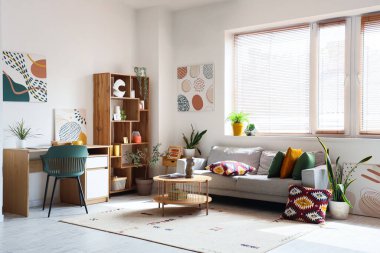 Rahat bir kanepe, işyeri, sehpa ve aydınlık oturma odasında resimler.