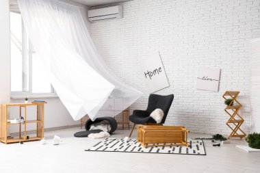 Koltuklu dağınık oturma odası ve ters çevrilmiş kahve masası.