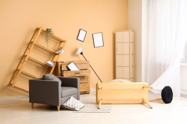 Koltuğu ve ters dönmüş masası olan dağınık bir oturma odası.