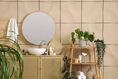 Lavabosu, raf ünitesi, çekmeceleri, çiçekleri ve aynası olan şık bir banyo.