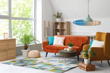 Kanepesi, koltuğu ve sörf tahtası olan modern bir oturma odası.