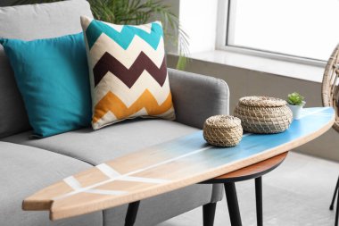 Oturma odasının içinde rahat bir kanepe ve sörf tahtası.